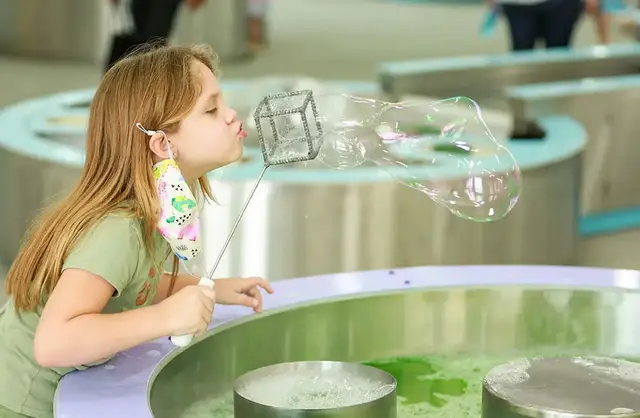 Child making a giant bubble at the Soap Bubble Maker